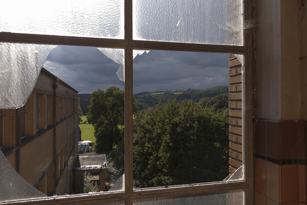 zicht op landschap door kapot raam van Sanatorium Dolhain